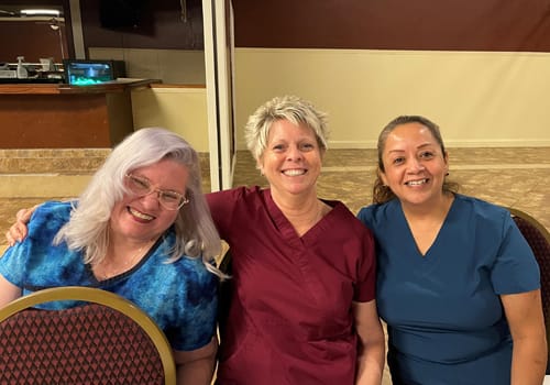 Three women smiling at a dinner event