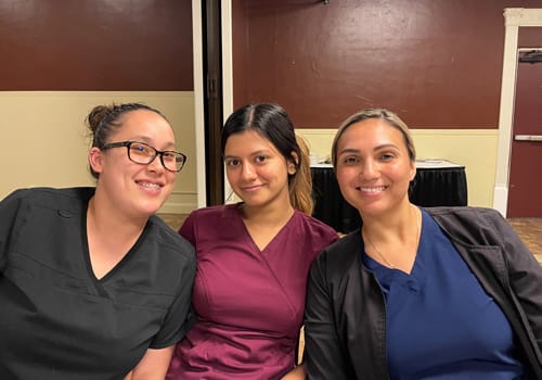 Three women smiling at a dinner event