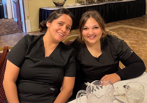 Two women smiling at a dinner event